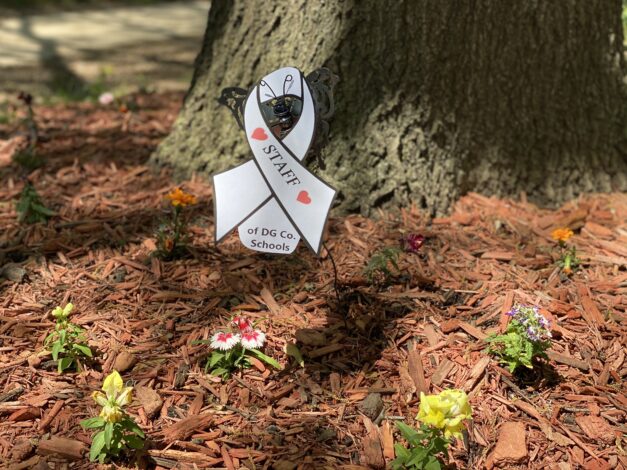 Ribbon supporting staff of Douglas County schools in flowerbed
