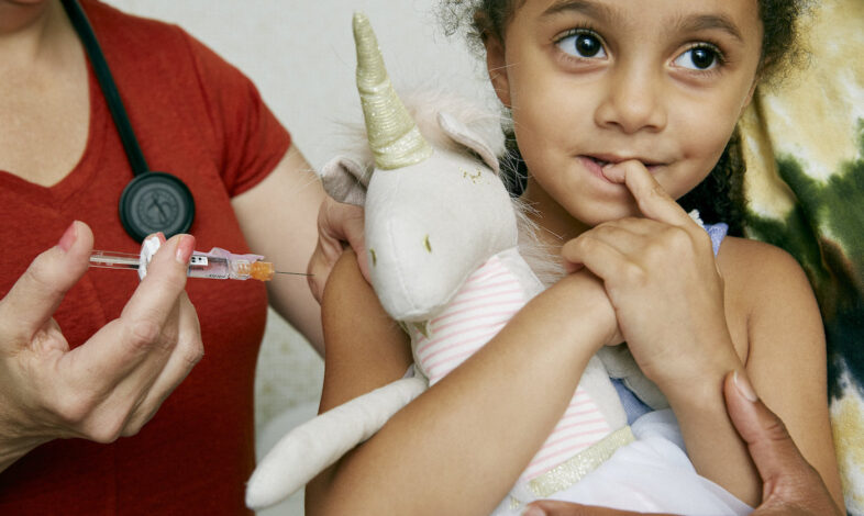 Happy young girl about to receive a vaccine from a medical professional